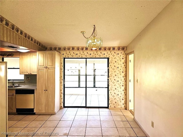 kitchen with light tile patterned floors, stainless steel dishwasher, a textured ceiling, and a notable chandelier