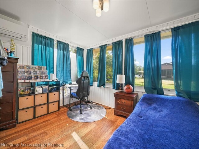 bedroom featuring multiple windows, hardwood / wood-style floors, and a wall mounted air conditioner