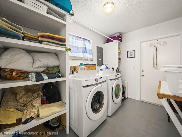 laundry room with a textured ceiling, washing machine and dryer, and electric panel