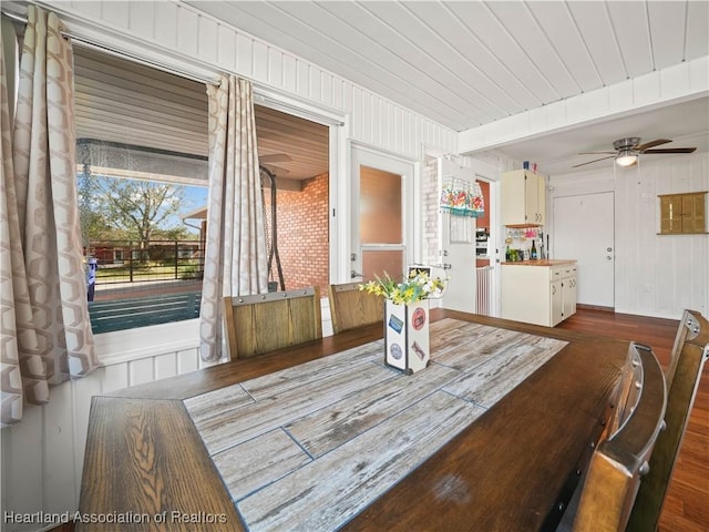 dining room with hardwood / wood-style flooring, ceiling fan, and wooden walls