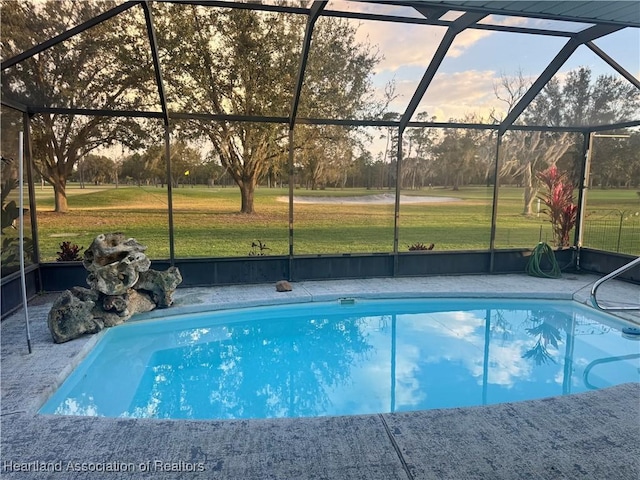 pool at dusk featuring a lanai and a yard