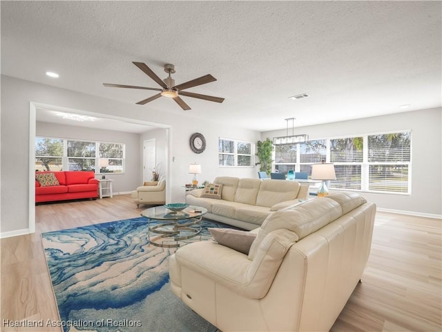 living room featuring ceiling fan, a textured ceiling, and light hardwood / wood-style floors