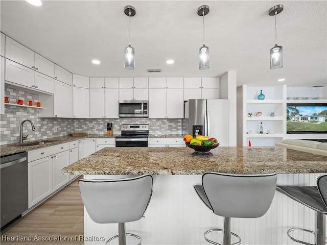 kitchen with white cabinetry, sink, pendant lighting, and stainless steel appliances