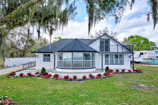 view of front of house with a front yard and a balcony