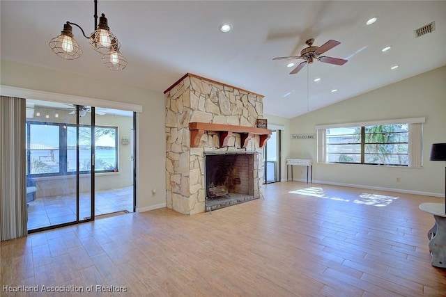 unfurnished living room featuring a fireplace, ceiling fan with notable chandelier, plenty of natural light, and light hardwood / wood-style flooring