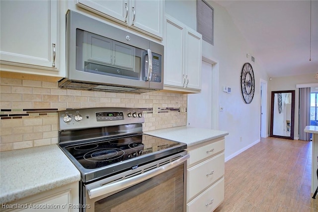 kitchen featuring white cabinets, light wood-type flooring, backsplash, and stainless steel appliances