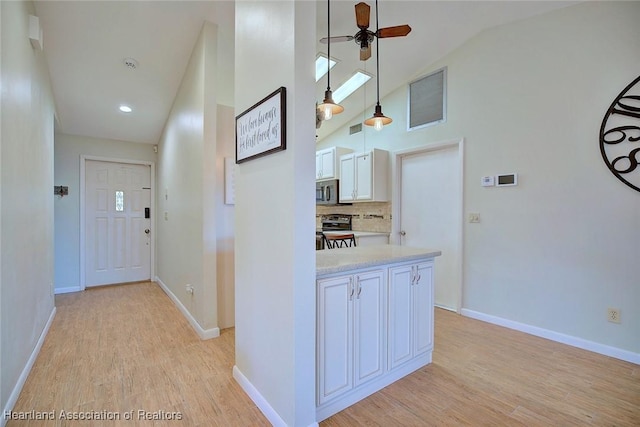 hallway with light hardwood / wood-style floors and high vaulted ceiling