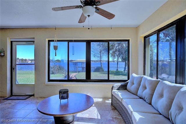 living room with a water view, a wealth of natural light, and ceiling fan