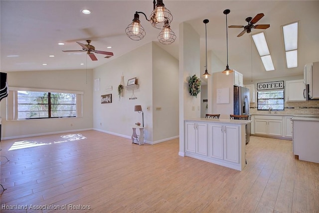 kitchen featuring ceiling fan with notable chandelier, decorative light fixtures, white cabinetry, and backsplash