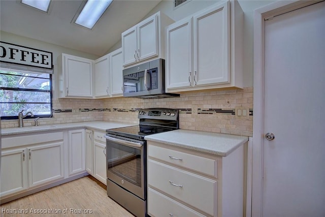 kitchen featuring sink, white cabinets, lofted ceiling, and appliances with stainless steel finishes