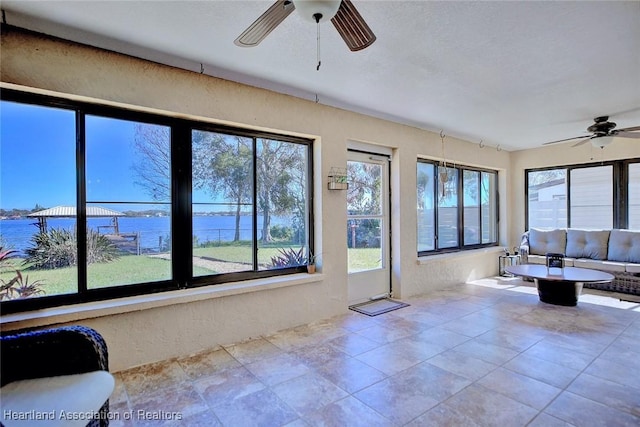 unfurnished sunroom with a water view, plenty of natural light, and ceiling fan