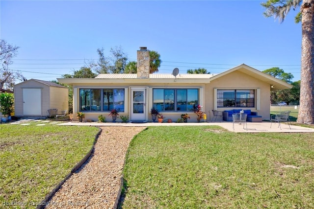 back of property featuring a lawn, a shed, and a patio