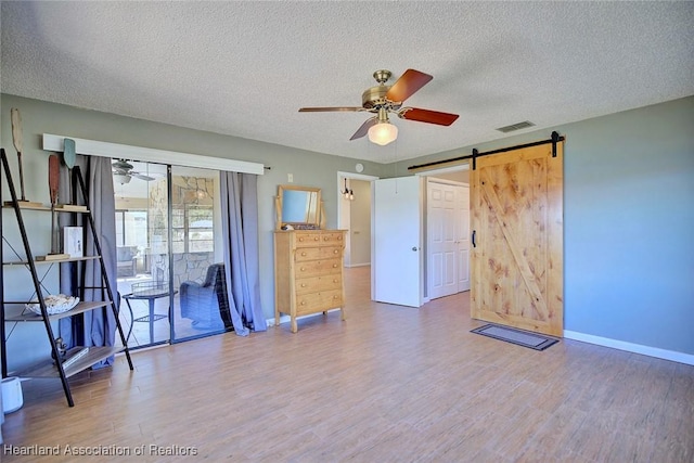 unfurnished room with hardwood / wood-style flooring, a barn door, and a textured ceiling