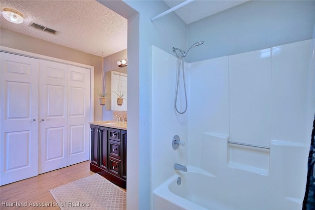 bathroom with shower / bath combination, a textured ceiling, vanity, and hardwood / wood-style flooring