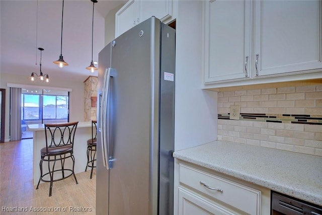 kitchen with light stone countertops, stainless steel appliances, decorative light fixtures, decorative backsplash, and white cabinets