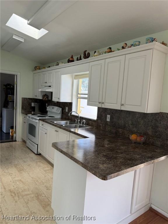 kitchen with vaulted ceiling with skylight, white range with electric stovetop, sink, white cabinets, and kitchen peninsula