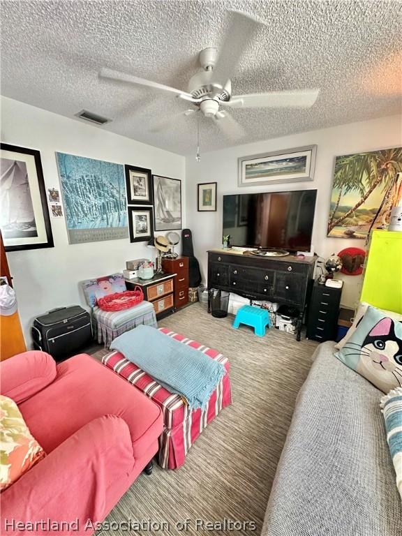 living room featuring carpet flooring, ceiling fan, and a textured ceiling