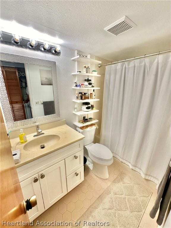 bathroom with a shower with curtain, tile patterned floors, a textured ceiling, toilet, and vanity