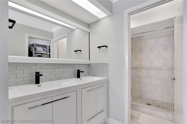 bathroom with backsplash, vanity, a tile shower, and ornamental molding