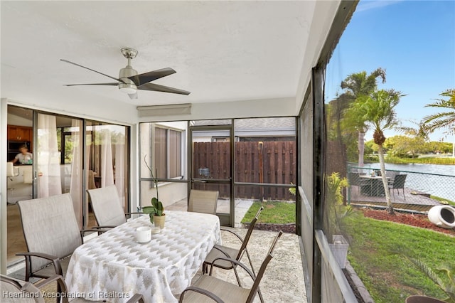 sunroom / solarium with a wealth of natural light, ceiling fan, and a water view