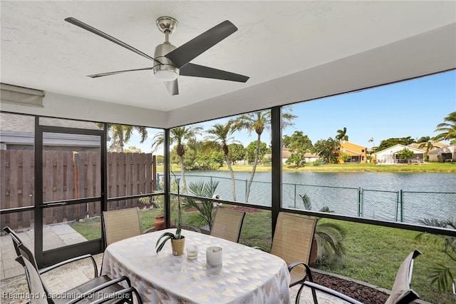 sunroom / solarium with a water view and ceiling fan