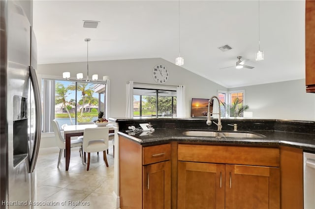 kitchen with sink, hanging light fixtures, dark stone counters, ceiling fan with notable chandelier, and appliances with stainless steel finishes