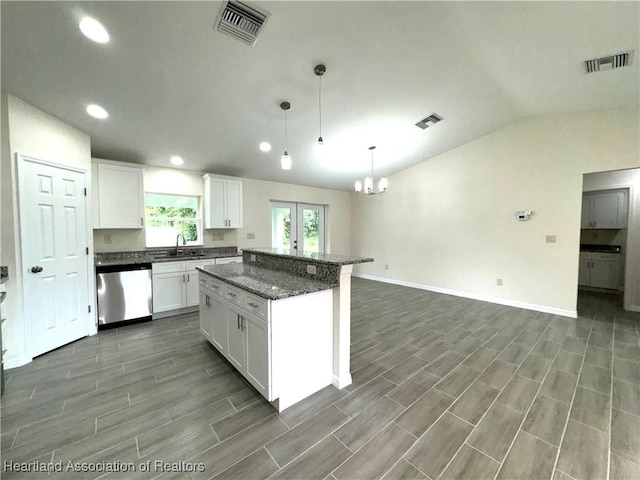 kitchen with sink, hanging light fixtures, vaulted ceiling, stainless steel dishwasher, and white cabinetry