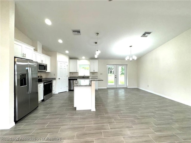 kitchen with white cabinets, stainless steel appliances, decorative light fixtures, and a kitchen island