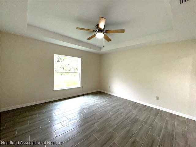 unfurnished room with ceiling fan and a raised ceiling