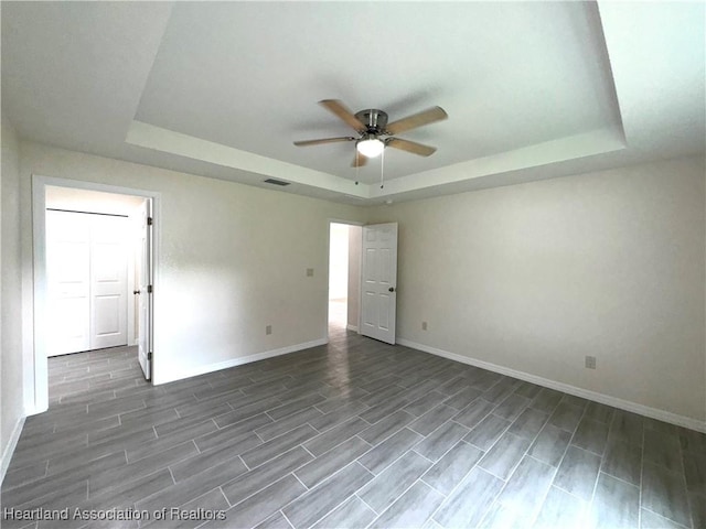 unfurnished room featuring a raised ceiling and ceiling fan