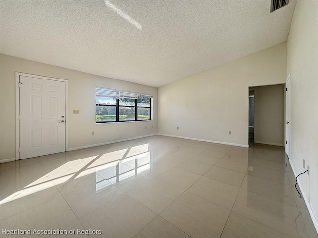 tiled empty room featuring a textured ceiling