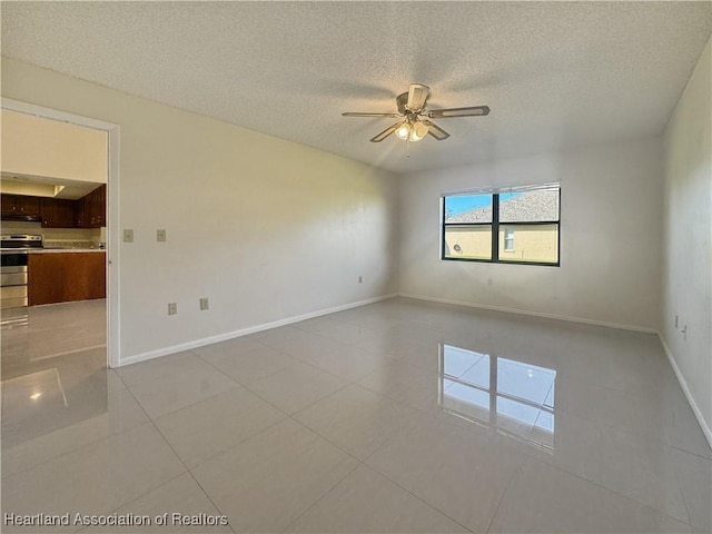 spare room featuring ceiling fan, light tile patterned floors, and a textured ceiling