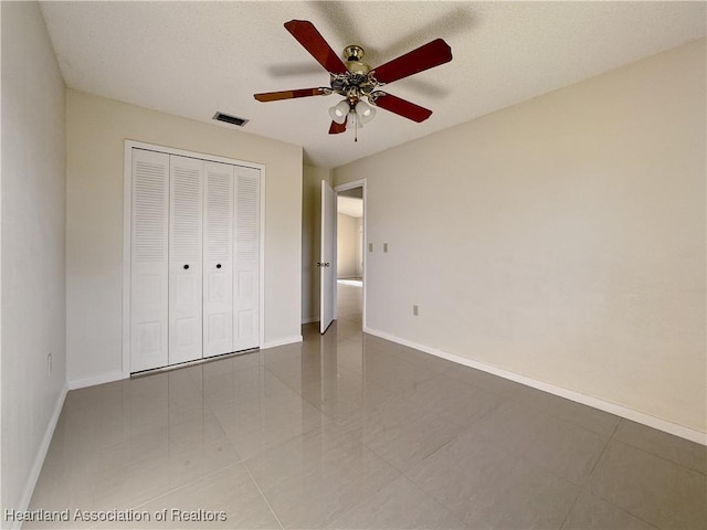 unfurnished bedroom featuring tile patterned floors, ceiling fan, a textured ceiling, and a closet