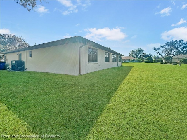 view of side of property featuring central AC unit and a lawn