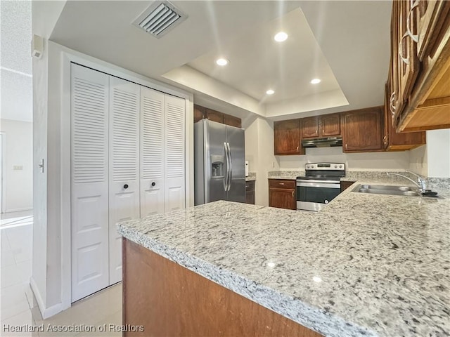 kitchen with sink, light tile patterned floors, light stone counters, kitchen peninsula, and stainless steel appliances