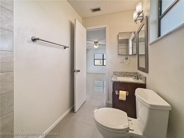 bathroom featuring ceiling fan, tile patterned flooring, a textured ceiling, toilet, and vanity