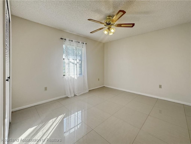 tiled spare room with a textured ceiling and ceiling fan