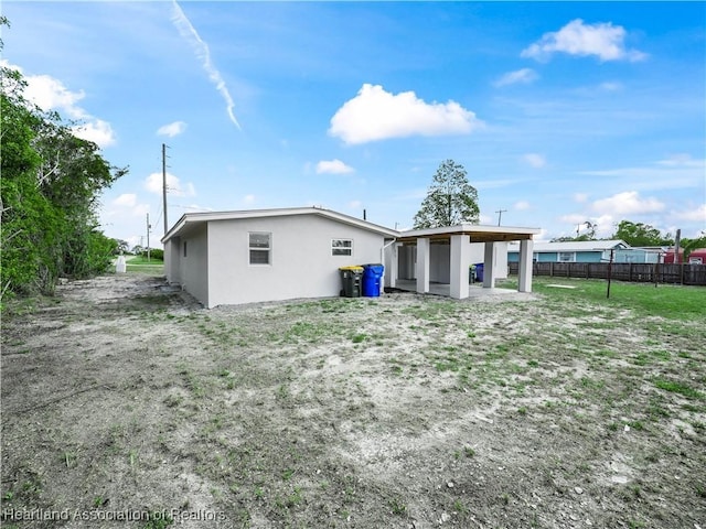 back of property with stucco siding and fence