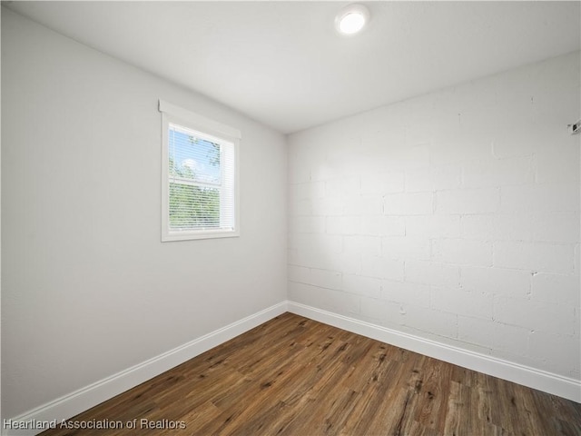 spare room with baseboards and dark wood finished floors