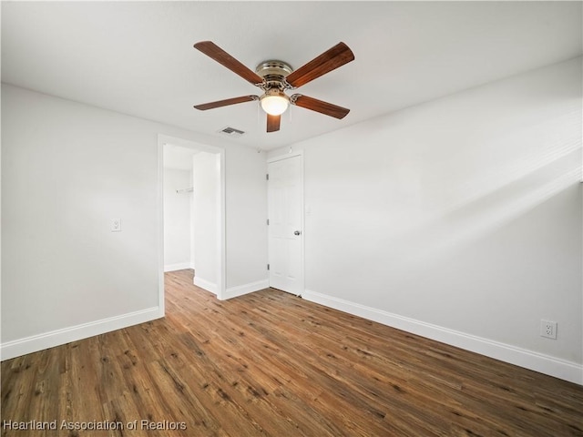 empty room featuring baseboards, visible vents, ceiling fan, and wood finished floors