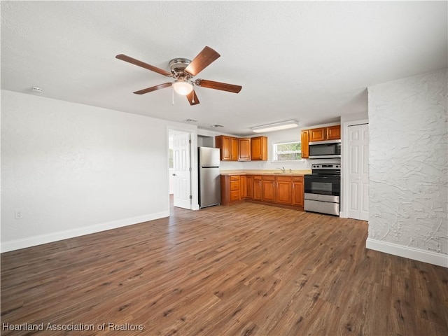 kitchen featuring light countertops, stainless steel appliances, baseboards, and wood finished floors