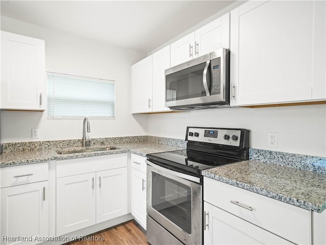 kitchen featuring a sink, light stone counters, white cabinets, and stainless steel appliances