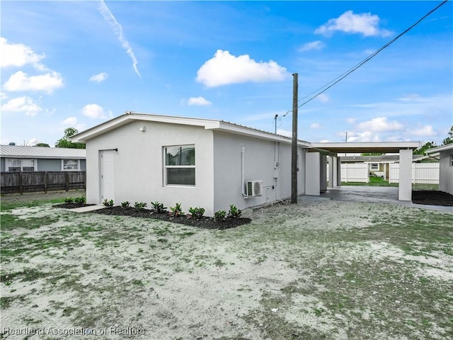 view of home's exterior with stucco siding, fence, and an attached carport