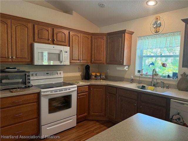 1502 Paper Birch St, Lake Placid, FL 33852 - kitchen featuring white appliances, a sink, vaulted ceiling, light countertops, and dark wood finished floors