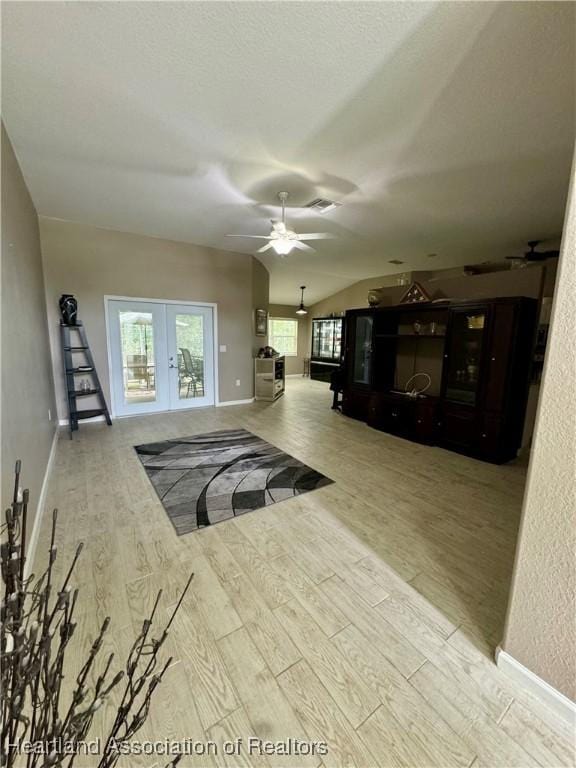 living room with french doors, light hardwood / wood-style flooring, vaulted ceiling, and ceiling fan