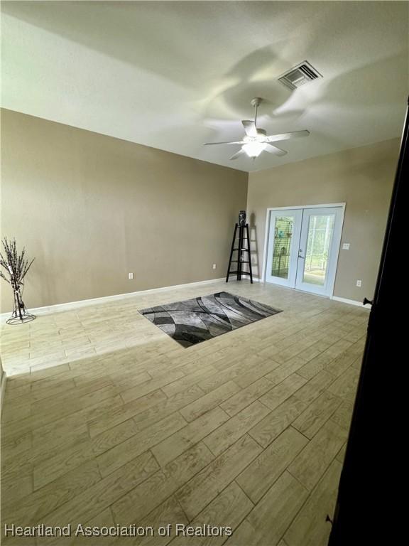 unfurnished living room with ceiling fan, french doors, and light wood-type flooring