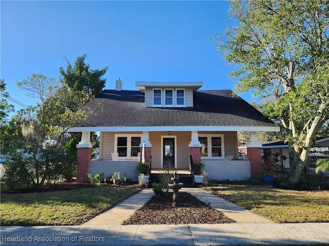 bungalow-style house with brick siding, a porch, and a front yard