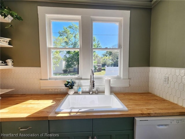 kitchen with dishwasher, a sink, backsplash, and wood counters