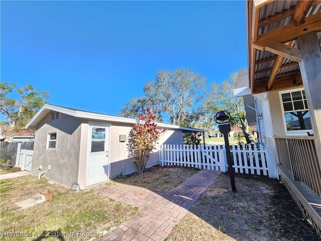 view of side of home with stucco siding, an outdoor structure, and fence