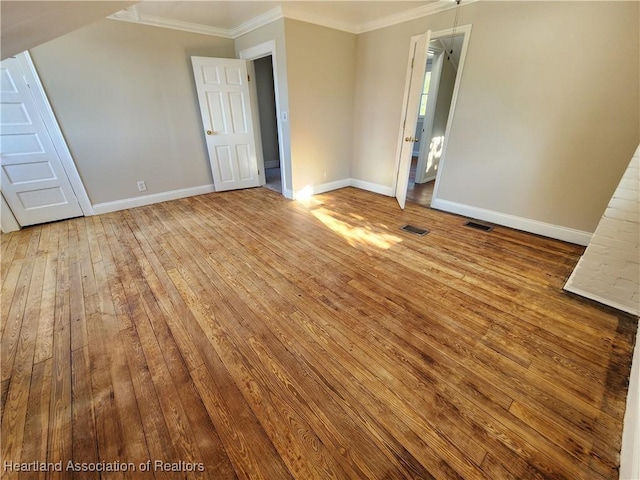 unfurnished room featuring visible vents, baseboards, hardwood / wood-style floors, and crown molding